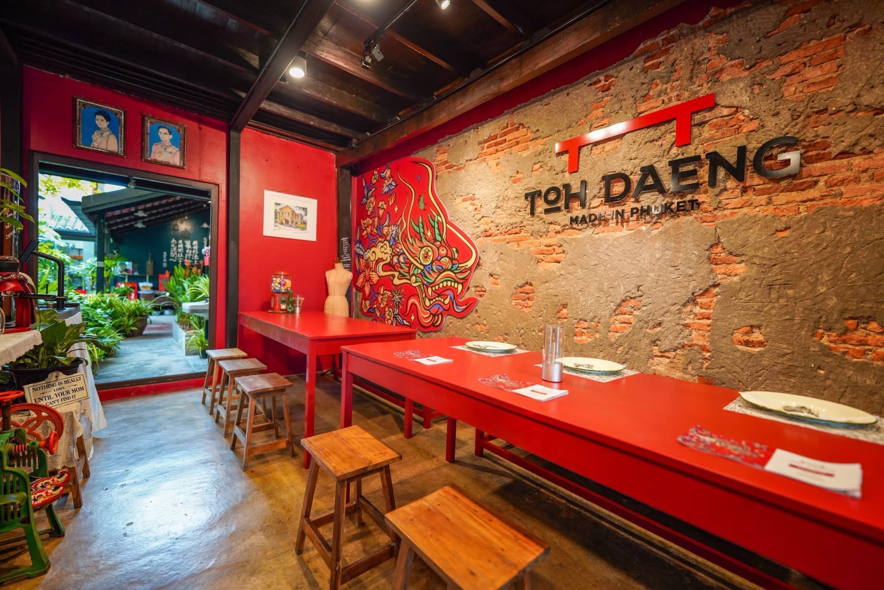 TOH DAENG communal dining room — long red tables and logo wall